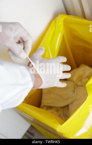 Chirurg trowing OP-Handschuhe in Papierkorb verwendet Stockfoto