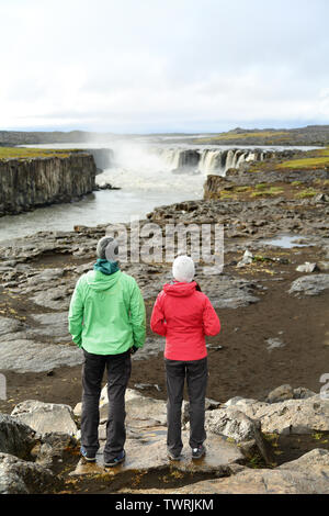 Wanderer auf Island Natur durch den Wasserfall Selfoss Wasserfall. Menschen mit Blick auf den berühmten isländischen touristische Attraktion. Wandern Paar unter Bruch von Selfoss in Vatnajökull National Park. Stockfoto