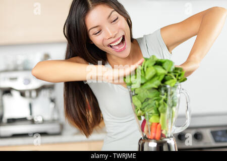 Pflanzliche smoothie Frau, die grüne Smoothies mit Blender zu Hause in der Küche. Gesunde Rohstoffe Essen lifestyle Konzept Portrait von schönen jungen Frau Vorbereitung Drink mit Spinat, Karotten, Sellerie etc. Stockfoto