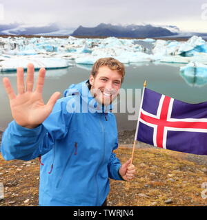 Island reisen Touristische Übersicht isländischer Flagge von Jokulsarlon ist. Mann Wanderer glücklich halten, isländischer Flagge vor dem Gletschersee/Gletscher Lagune. Gerne männliche im Tourismus Konzept lächelnd. Stockfoto