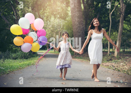 Ich liebe Mama bleiben zusammen am Muttertag. Adorable cute girl Holding Luftballons mit Mutter zu Fuß auf dem Weg in den Park. Familie Konzept. Stockfoto