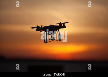 Eine DJI-Phantom3 Pro Drohne Schweben mit einem bunten Sonnenuntergang als Hintergrund Stockfoto