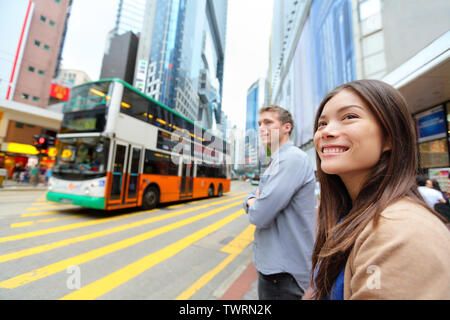 Die Menschen in Hongkong zu Fuß in Causeway Bay überqueren sehr befahrenen Straße mit Double Decker Bus. Urban Mixed Race asiatische Chinesische/Kaukasischen lächelnde Frau glückliches Leben in der Stadt. Stockfoto