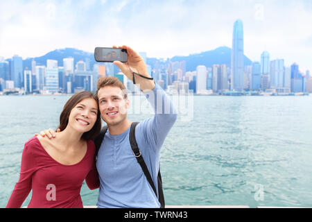 Selfie Touristen Paar unter Selbstporträt bild Fotos in Hongkong genießen Sightseeing auf Tsim Sha Tsui Promenade und Avenue der Stars im Victoria Harbour, Kowloon, Hong Kong. Travel Concept. Stockfoto