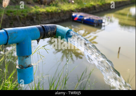 Landwirtschaft blaue Leitung, die mit dem Grundwasser in Teich strömte Stockfoto