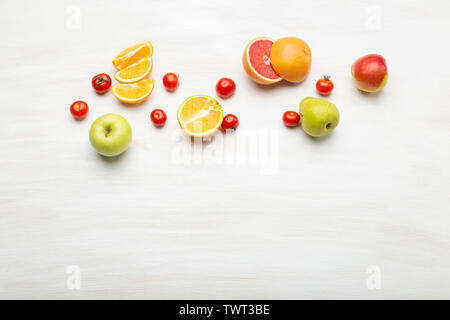 Verschiedene Obst orange Scheiben in Birnen und Äpfel liegen in der Nähe von roten Tomaten auf einem weißen Tisch mit kopieren. Veganes essen Konzept. Werbeflächen Stockfoto