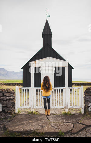 Frau Suchen auf der berühmten Schwarzen Kirche von Budir auf Snaefellsnes Halbinsel Region in Island. Auf Island Willkommen. Herbst. Stockfoto