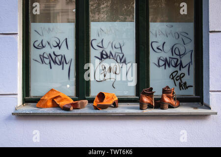 Schuhe auf einem Fenstersims aufgegeben Neben einem Graffiti-Fenster zu einem städtischen Still Life Stockfoto