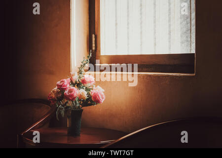 Plastikblumen in den alten Töpfen erhalten Sonneneinstrahlung von der Seite des Fensters. Stockfoto