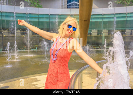 Fontäne des Reichtums an Suntec Tower, der größte Brunnen in Singapur. Lifestyle touristische berühren Wasser der Brunnen für besseres Glück. Blond kaukasischen Stockfoto