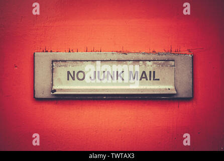 Ein Briefkasten auf einem Grungy Orange Tür mit einem keine Junk-E-Mail anmelden Stockfoto