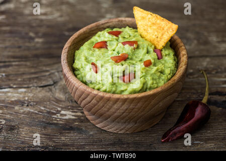 Guacamole in Houten mit Tortilla Chips und Chili auf rustikalem Holz Stockfoto