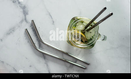 Metall Trinkhalme und kalten Getränk im Glas Marmeladenglas auf weißem Hintergrund. Top View oder flach. Kopieren Sie Platz für Text oder Design. Recyclingfähige Trinkhalme, null Abfall Konzept. Banner. Stockfoto