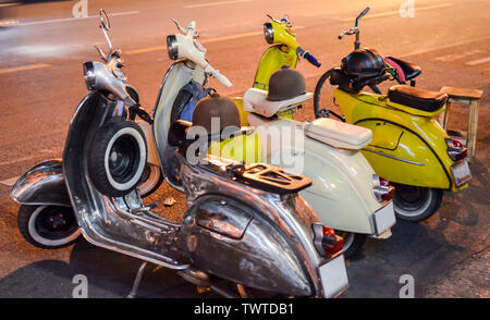 Classic Scooter am Abend auf der Straße. Drei Oldtimer Roller, Schwarz, Weiß und Gelb. Abends Straße Fotografie Stockfoto