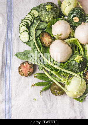 Verschiedene grüne Gemüse heap auf Licht Tabelle: Grüne Erbsen, Kohlrabi, Kopfsalat, Zucchini, Gurken, grüne Tomaten. Ansicht von oben. Reinigen Sie vegetarisches Essen ein Stockfoto