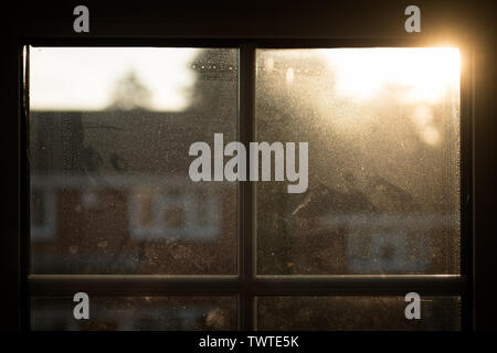 Sonnenaufgang über Dach, durch das Haus Fenster gesehen, die durch Staub und Kondenswasser beschlagenen; Querformat. Stockfoto