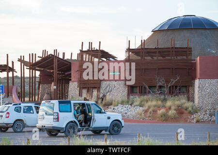 Hauptrezeption Gebäuden in der Kgalagadi Transfrontier Park, Südafrika mit Autos auf dem Parkplatz am Abfahrtspunkt oder Ausfahrt Bereich geparkt Stockfoto