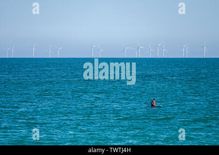 Ein Paddel boarder schaut in Richtung der Rapunzeln Windpark vor der Küste von West Sussex, UK. Stockfoto