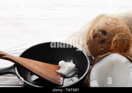 Kokosnuss, Shell mit Fleisch, Gusseisen Skillet und Spachtel auf Hanf Sack auf weißen Küche aus Holz Tisch Stockfoto