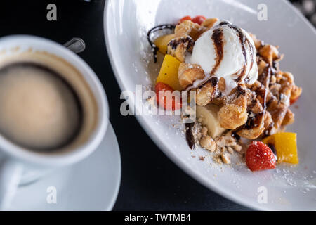 Waffeln mit Eis bedeckt Schokolade und mit Obst auf einem Teller auf den Tisch eingerichtet. Stockfoto