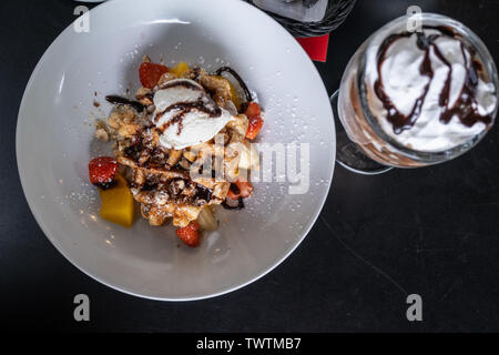 Waffeln mit Eis bedeckt Schokolade und mit Obst auf einem Teller auf den Tisch eingerichtet. Stockfoto