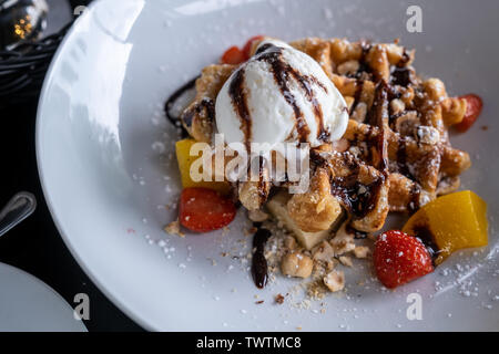 Waffeln mit Eis bedeckt Schokolade und mit Obst auf einem Teller auf den Tisch eingerichtet. Stockfoto