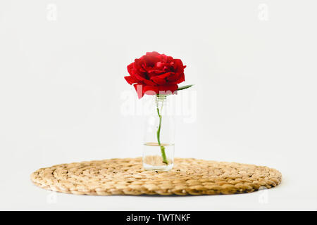 Rote Rosen in Glas Vasen auf einem Natur wicker Serviette auf weißem Hintergrund Stockfoto