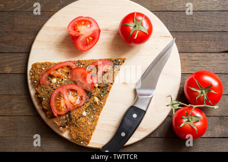 Rohkost Konzept. Dehydriert raw vegan trockenem Brot, geschnitten und ganze rote Kirschtomaten, Messer auf Küche Board auf Holztisch. Gesunde nutritio Stockfoto