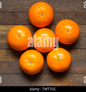 Mandarinen in Sternform auf hölzernen Tisch. Frische orange Früchte. Ansicht von oben. Close Up. Gesunde Ernährung Konzept. Rohe Lebensmittel. Ernte von Mandarinen Stockfoto