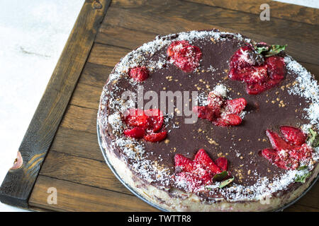 Leckere Schokolade hausgemachte vegane Kuchen auf Holz fach Gesunde Süßigkeiten. Rohe Lebensmittel. Natürliche Schokolade, bestreut mit carob Pulver und Kokos Chips. Str Stockfoto