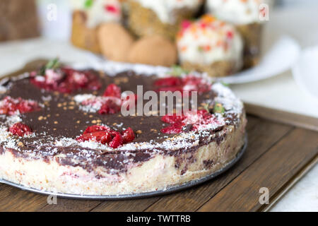 Gesunde Süßigkeiten Konzept. Сhocolate hausgemachte vegane Kuchen auf Holz Fach rohe Nahrungsmittel. Erdbeeren, natürliche Schokolade, bestreut mit carob Pulver und coconu Stockfoto