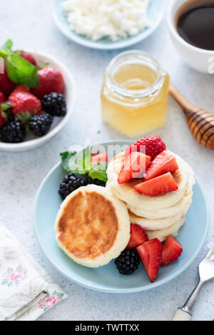 Quark Pfannkuchen, Quark Krapfen, Syrniki mit Honig und Beeren Stockfoto