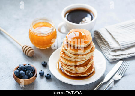 Buttermilch Pfannkuchen mit Honig, Sirup, Tasse Kaffee und frischen Blaubeeren Stockfoto