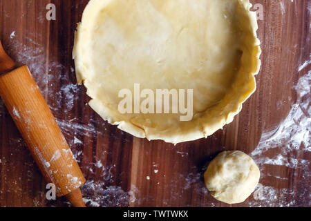 Kochvorgang. Indoor American Apple Pie mit mürbteig Gebäck auf einem dunklen Hintergrund. Rohen Teig gerollt. Blick von oben. Kopieren Sie Platz. Flach Stockfoto