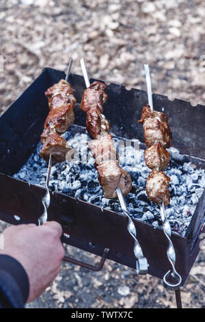 Mann hält in der Hand einen Spieß mit rohem Fleisch, Life Style. Stockfoto