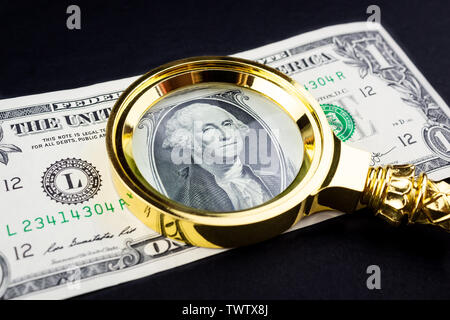 Lupe liegt auf amerikanische Dollar auf schwarzem Hintergrund Stockfoto