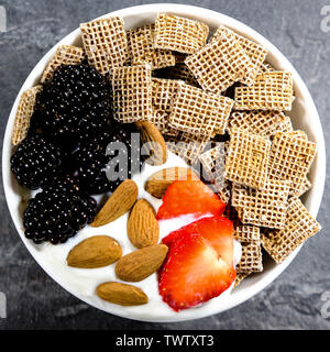 Gesundes Frühstück Müsli mit frischem Obst, shreddies oder zerkleinert Weizen, Erdbeeren, Brombeeren, Mandeln und Joghurt. Stockfoto