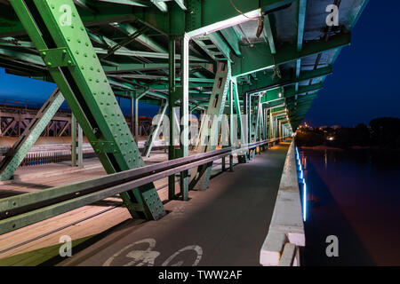 Gdanski Bridge bei Nacht in Warschau, Polen, Stahlkonstruktion mit Straßenbahn Schienen- und Radweg, der Hauptstadt Infrastruktur, Fluchtpunkt perspecti Stockfoto