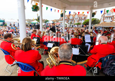 Broadstairs Musikpavillon an der Strandpromenade. Band, Orchester in Rot militärische Uniformen gekleidet im Musikpavillon. In der Nähe von hinter der Band, über die Schulter sehen, Weitwinkel. Dirigent und Publikum. Stockfoto