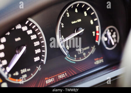 Elektronisches Armaturenbrett des modernen Luxus auto Blick von der Seite. Tachometer verschwommen mit selektiven Fokus auf den Pfeil und Tachometer und Kilometerzähler. Stockfoto