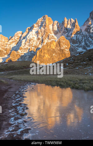 Goldene Berge auf dem Wasser auf einem zugefrorenen See in den italienischen Dolomiten wider. Mountain Range während der Goldenen Stunde, Wasser Reflexionen von Gipfeln. Stockfoto