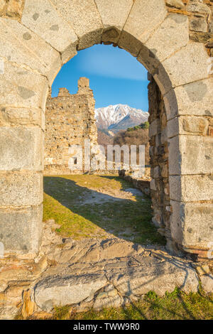 Schneebedeckte Berge Blick durch Steinbogen, mittelalterlichen Burgruinen in Cimbergo, Val Camonica. Alte Festung in den Bergen von Italien. Stockfoto