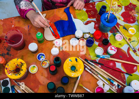 Russland, Jaroslawl Stadt - Mai 4, 2019: Das Kind hält einen Pinsel. Färbung ein Holzbrett. Creative Studio oder Zeichnung Lektion. Ausbildung Stockfoto