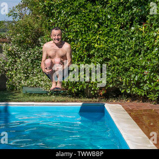 Kaukasische Mann nimmt eine Bombe Tauchgang im Pool mit einem lustigen Ausdruck Stockfoto