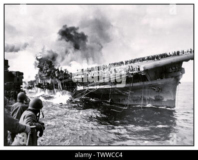 WW2 Bild der Flugzeugträger USS Franklin (CV-13) im Pazifik während des Zweiten Weltkriegs angegriffen, 19. März 1945. Von PHC Albert Farren aus der Kreuzer USS Santa Fe (CL-60), die neben einer Unterstützung bei der Brandbekämpfung und Rettung Arbeit fotografiert wurde. Der Träger ist auf Feuer und Auflistung, nachdem Sie von einem japanischen Luftangriff während vor der Küste Japans - die Mannschaft ist eindeutig auf Flight Deck gesehen, geschlagen wurde. Nach dem Angriff des Schiffes tot im Wasser lag, nahm einen 13° Steuerbord Liste, alle Radio Communications verloren, und gebratenem unter der Hitze von umhüllenden Brände. Stockfoto