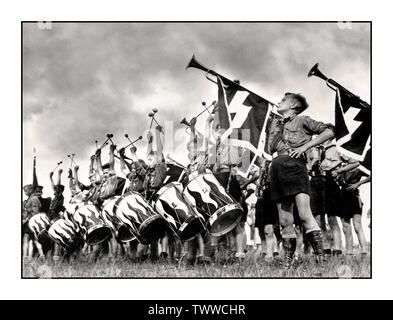 HITLER-JUGENDJUNGEN UNIFORMEN FANFARE TROMMELN Vintage Nazi-Deutschland-Rallye Propagandabild junger deutscher Hitler-Jugendjungen bei einer Kundgebung mit Messinghörnern und Trommeln in Nürnberg Fields Germany 1935. Die Hitlerjugend war eine logische Erweiterung Hitlers Überzeugung, dass die Zukunft des Nazi-Deutschlands seine Kinder sei. Die Hitlerjugend galt als ebenso wichtig für ein Kind wie die Schule. In den frühen Jahren der NS-Regierung machte Hitler deutlich, wie er deutsche Kinder erwarten würde. Stockfoto