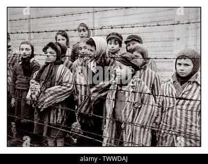 AUSCHWITZ 1945 KINDER GEFANGENEN BEFREIUNG Kind Gefangenen tragen gestreifte Uniformen starren heraus zu ihren Befreier von hinter einem Stacheldrahtzaun in berüchtigten WW2 NS-Tod-lager Auschwitz im südlichen Polen. Zweiten Weltkrieg Zweiten Weltkrieg Stockfoto