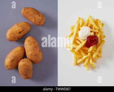 Mehrere ganze Kartoffeln und Haufen von Pommes mit Ketchup auf über zwei Ton rosa und lila Hintergrund Stockfoto