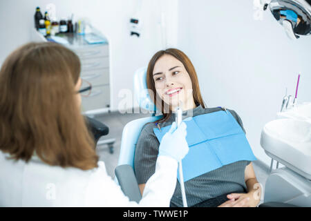 Lächelnde Mädchen behandelt, Zähne, während in den zahnmedizinischen Stuhl beim Arzt sitzen. Stockfoto