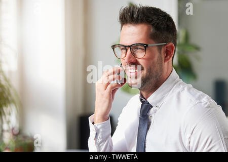 Close-up Portraitfotos der stattlichen Geschäftsmann mit Hemd und Krawatte im Büro sitzt und spricht mit jemand auf seinem Handy. Stockfoto